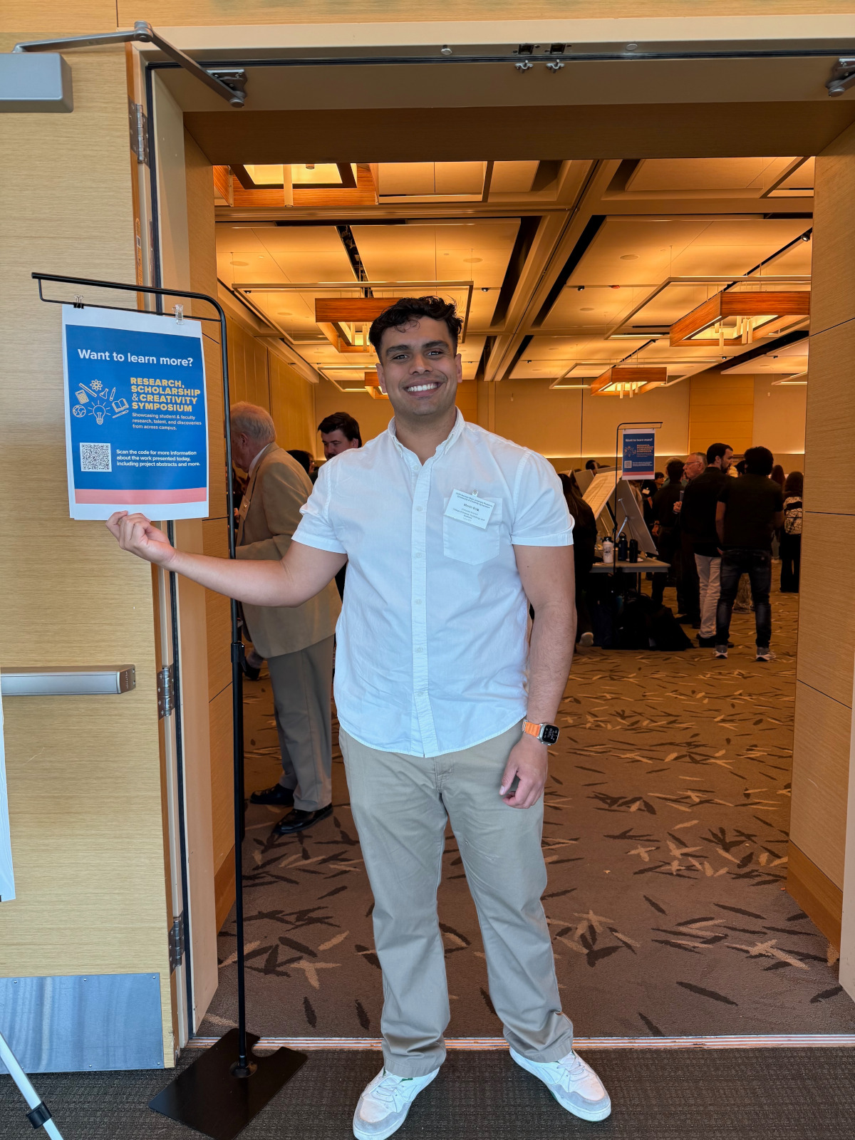Martin Bolz, a computer science graduate, smiling at a university research symposium.