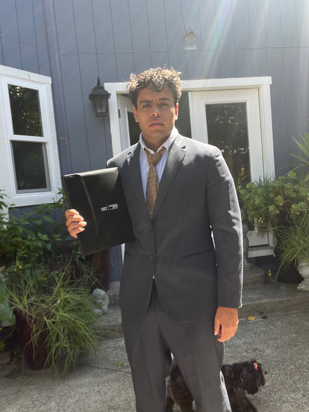 Martin Bolz in a suit holding his university diploma cover.